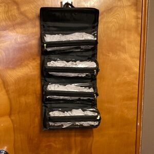 JOY MANGANO. TRAVEL BAG. BLACK WITH 4 SEE THRU COMPARTMENTS. HANDLE FOR HANGING